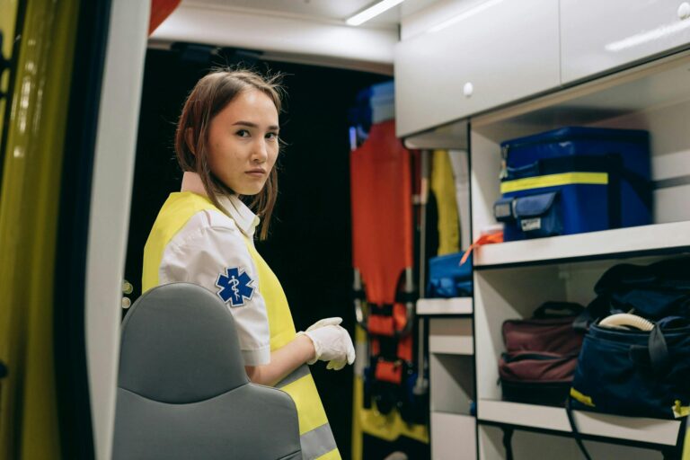 Young female paramedic inside an ambulance wearing a reflective vest at night.